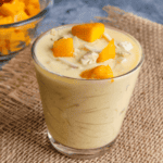 Mango semiya payasam served in a glass and garnished with ghee roasted nuts and fresh mango pieces.