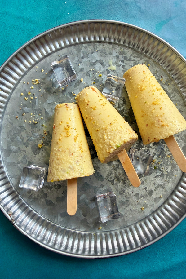 Rich malai kulfi garnished with powdered nuts served on a plate with ice cubes