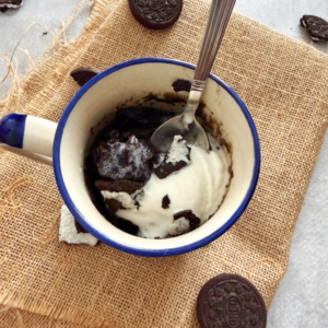 1 minute oreo mug cake topped with vanilla ice cream ready to be enjoyed