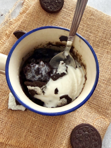 1 minute oreo mug cake topped with vanilla ice cream ready to be enjoyed