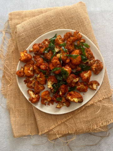 Crispy cauliflower 65 served with curry leaves garnish on a plate