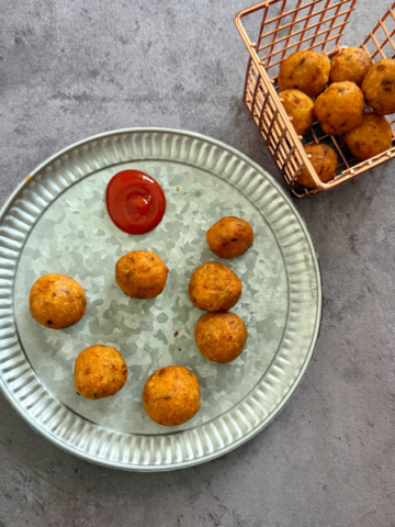 Crispy and golden brown potato balls served on a plate with kwtchup on the side